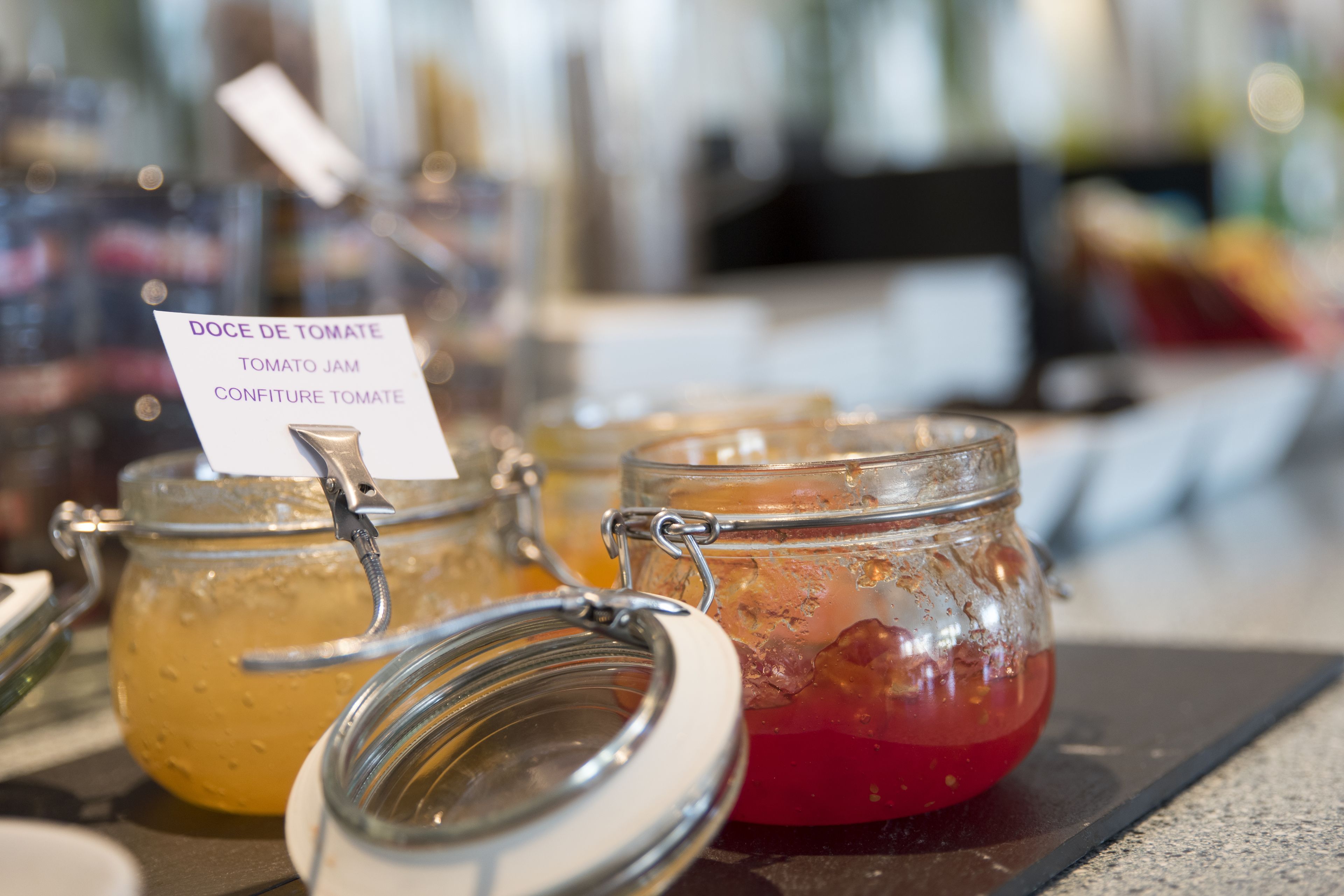 A display of food items with labels, including a jar of tomato jam and a jar of tomato juice.