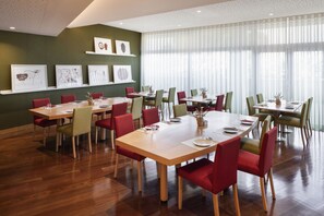 A dining area with multiple tables and chairs, framed artwork on the walls, and large windows with sheer curtains. - Mercure Porto Gaia Hotel (Vila Nova de Gaia)