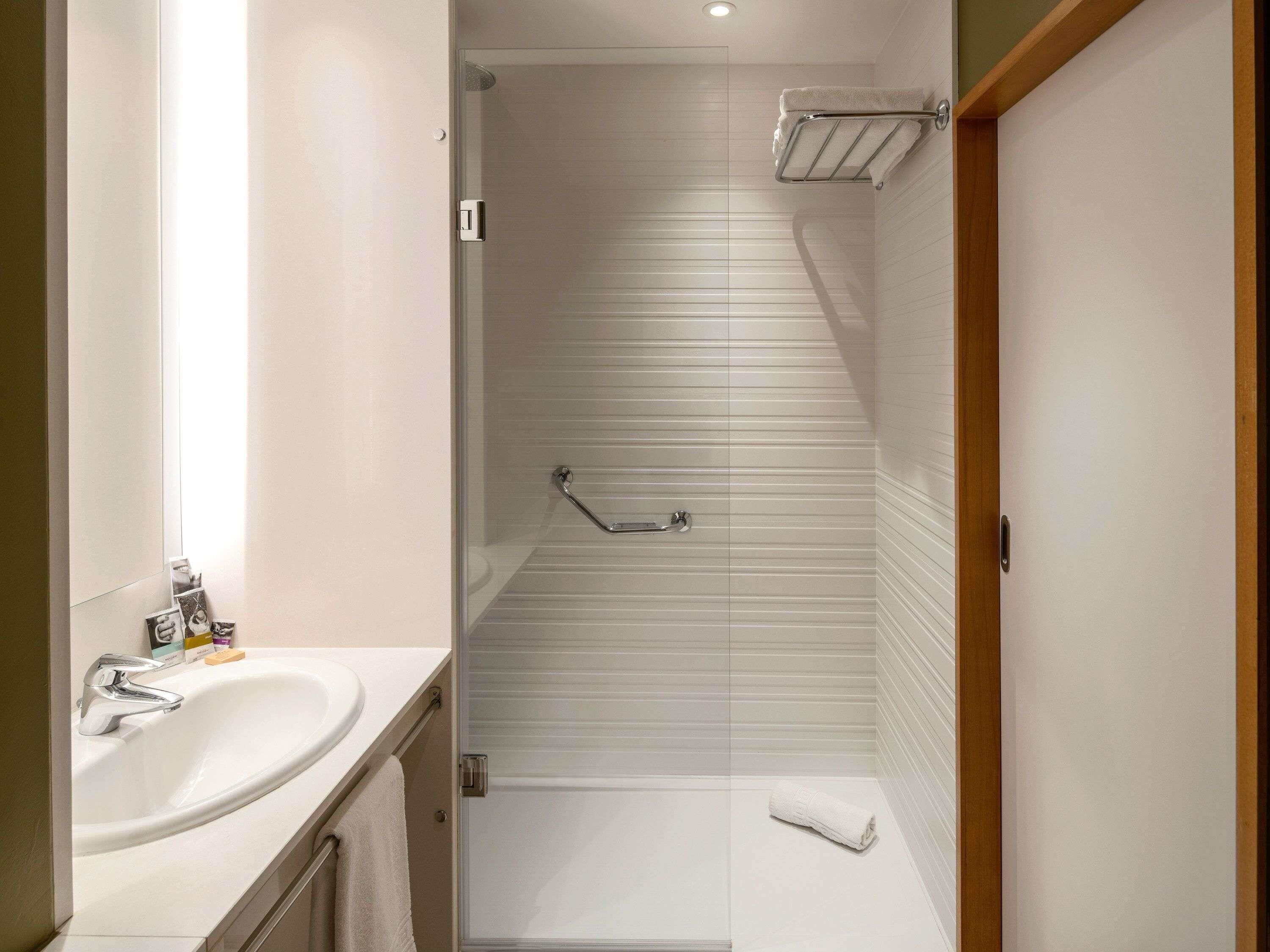 Une salle de bain moderne équipée d’une douche, d’un lavabo et d’un porte-serviettes.