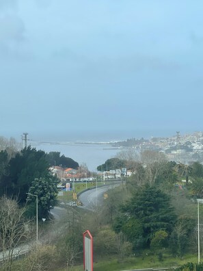 A coastal cityscape with a prominent red landmark, a curved road, and dense greenery. - Mercure Porto Gaia Hotel (Vila Nova de Gaia)