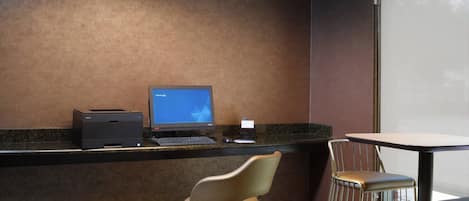 A reception desk with a computer, printer, and two chairs.