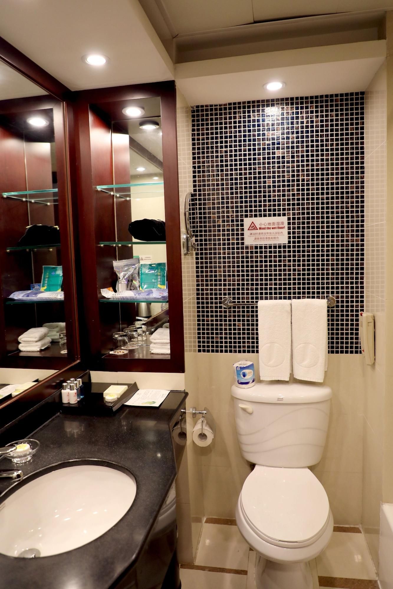 A bathroom with a sink, mirror, toilet, and a tiled shower area.