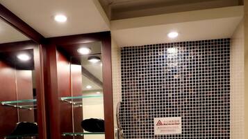 A bathroom with a sink, mirror, toilet, and a tiled shower area.