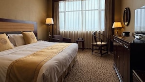 Ein Hotelzimmer mit einem großen Bett, einem Schreibtisch, einem Stuhl und einem fenster mit Vorhängen.