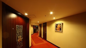Ein Hotelgang mit rotem Teppich, Holztüren und einem gerahmten Bild an der Wand.
