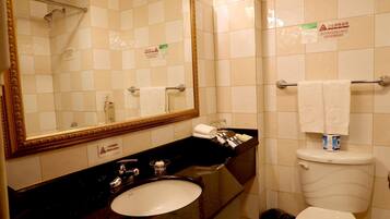 Une salle de bain avec un lavabo, un miroir et des toilettes. On y trouve des panneaux sur les murs, un porte-serviettes et une poubelle.