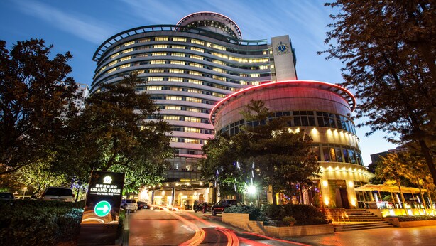Un hotel moderno con fachada curva, una entrada destacada y un cartel que indica Grand Park.