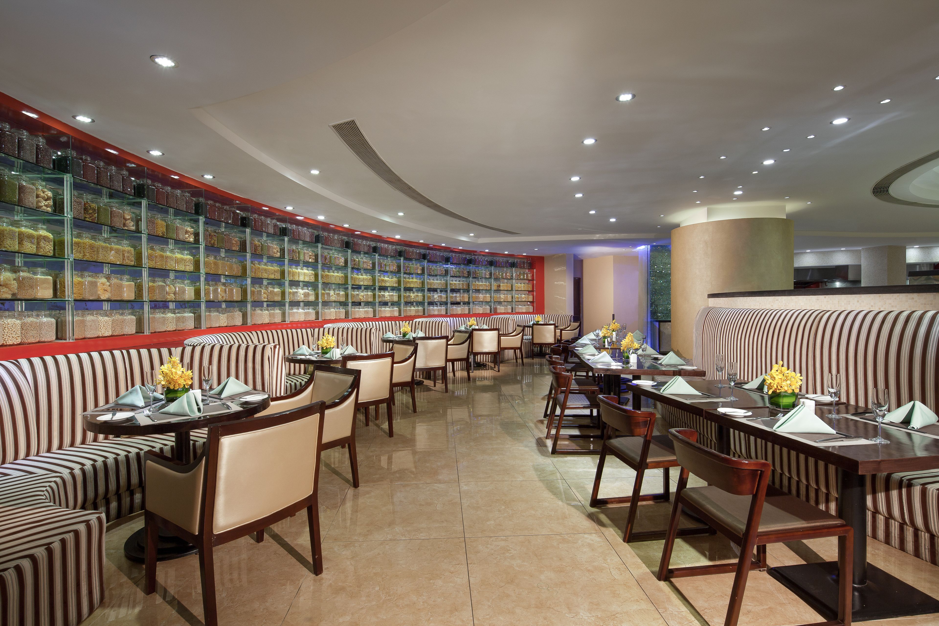 A restaurant with striped booths and tables, a curved ceiling, and a wall of jars.