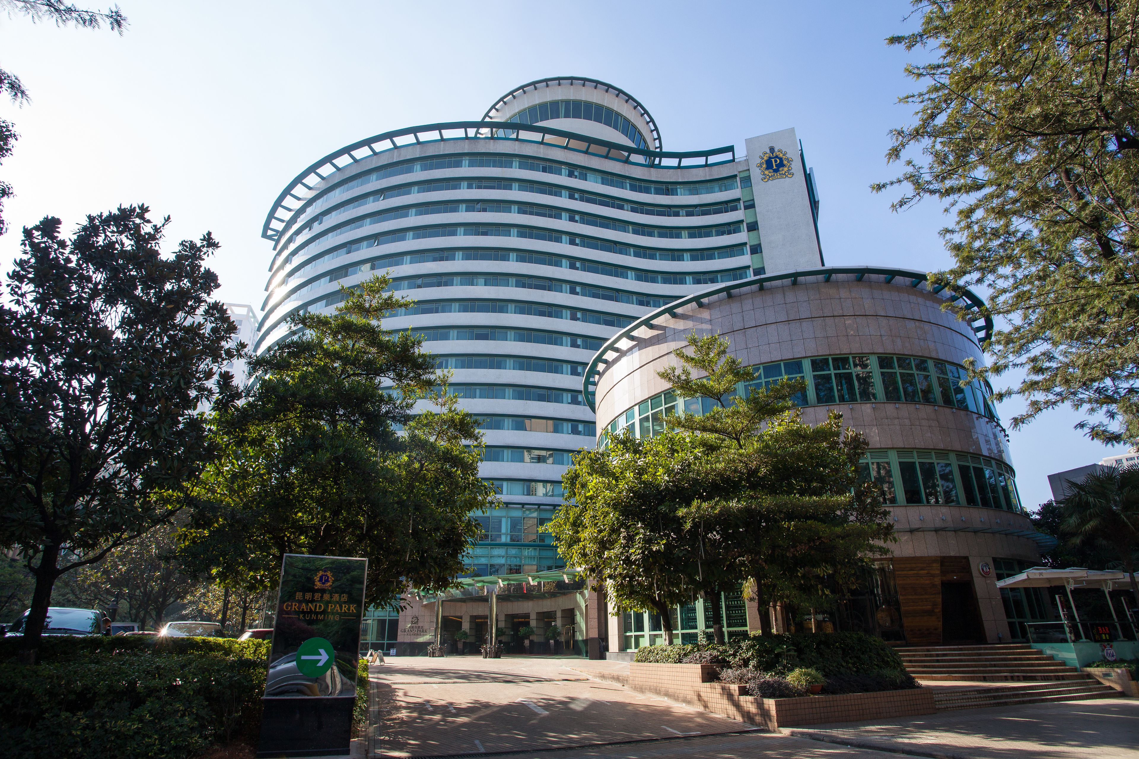 A modern hotel with a curved facade, multiple floors, and a prominent entrance with steps.