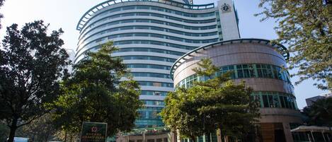 A modern hotel with a curved facade, multiple floors, and a prominent entrance with steps.