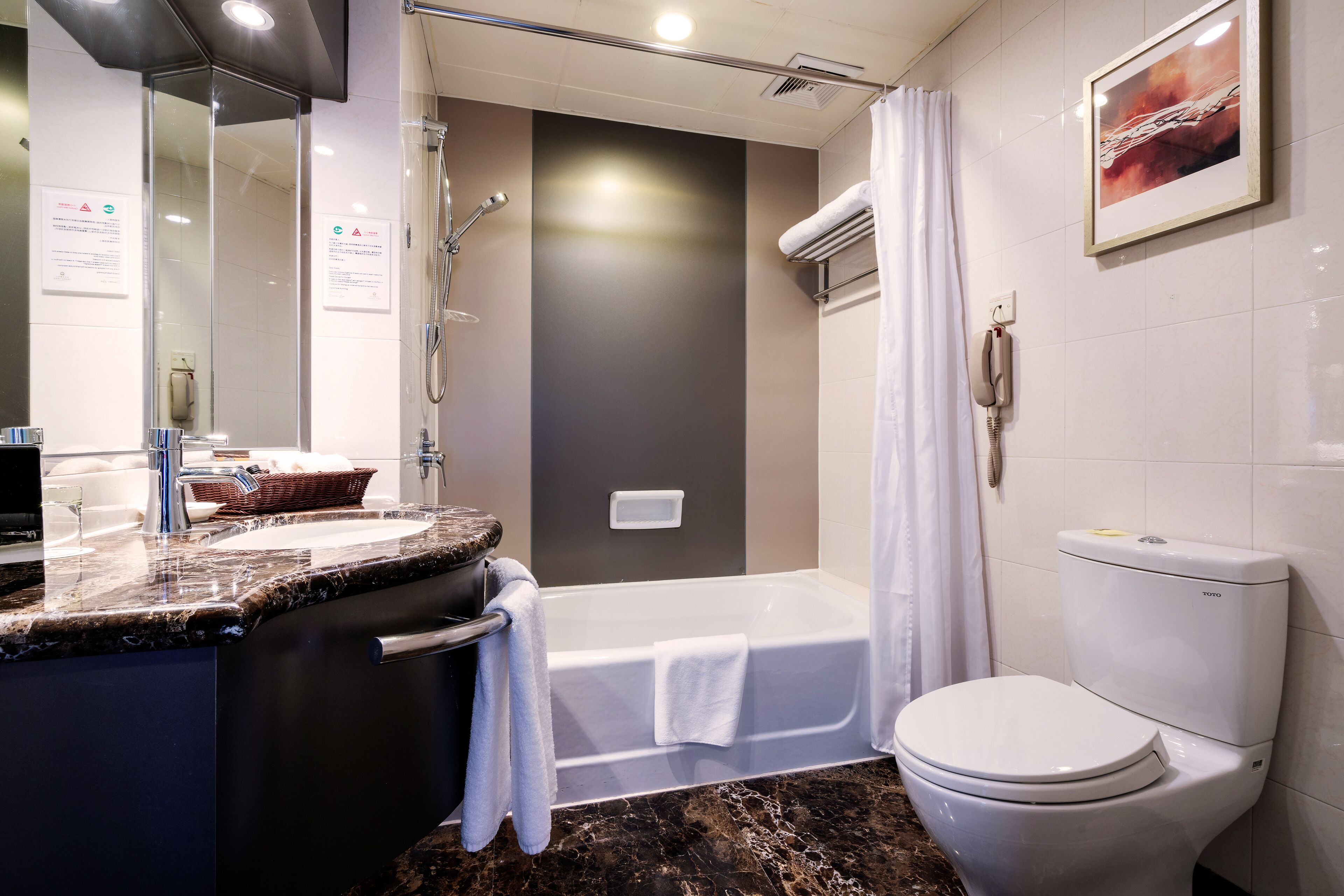 A modern bathroom with a bathtub, toilet, and two sinks.