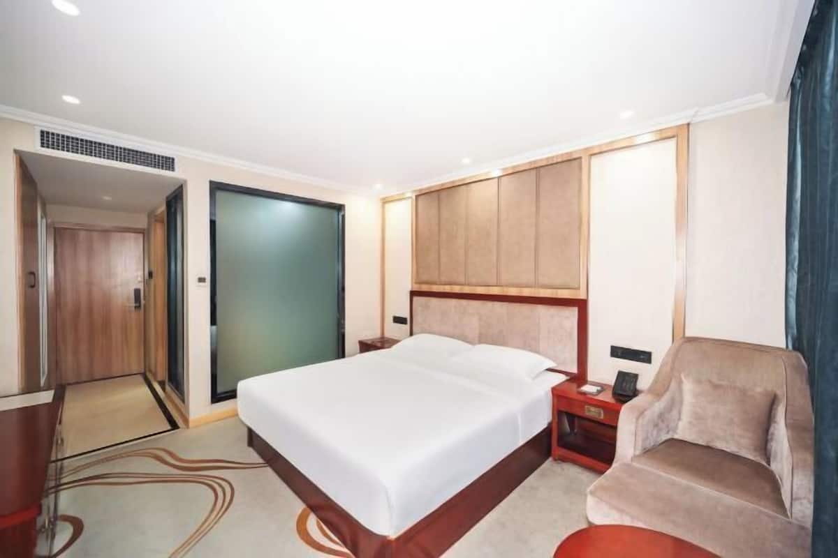 A hotel room with a bed, a desk, a chair, and a wardrobe.
