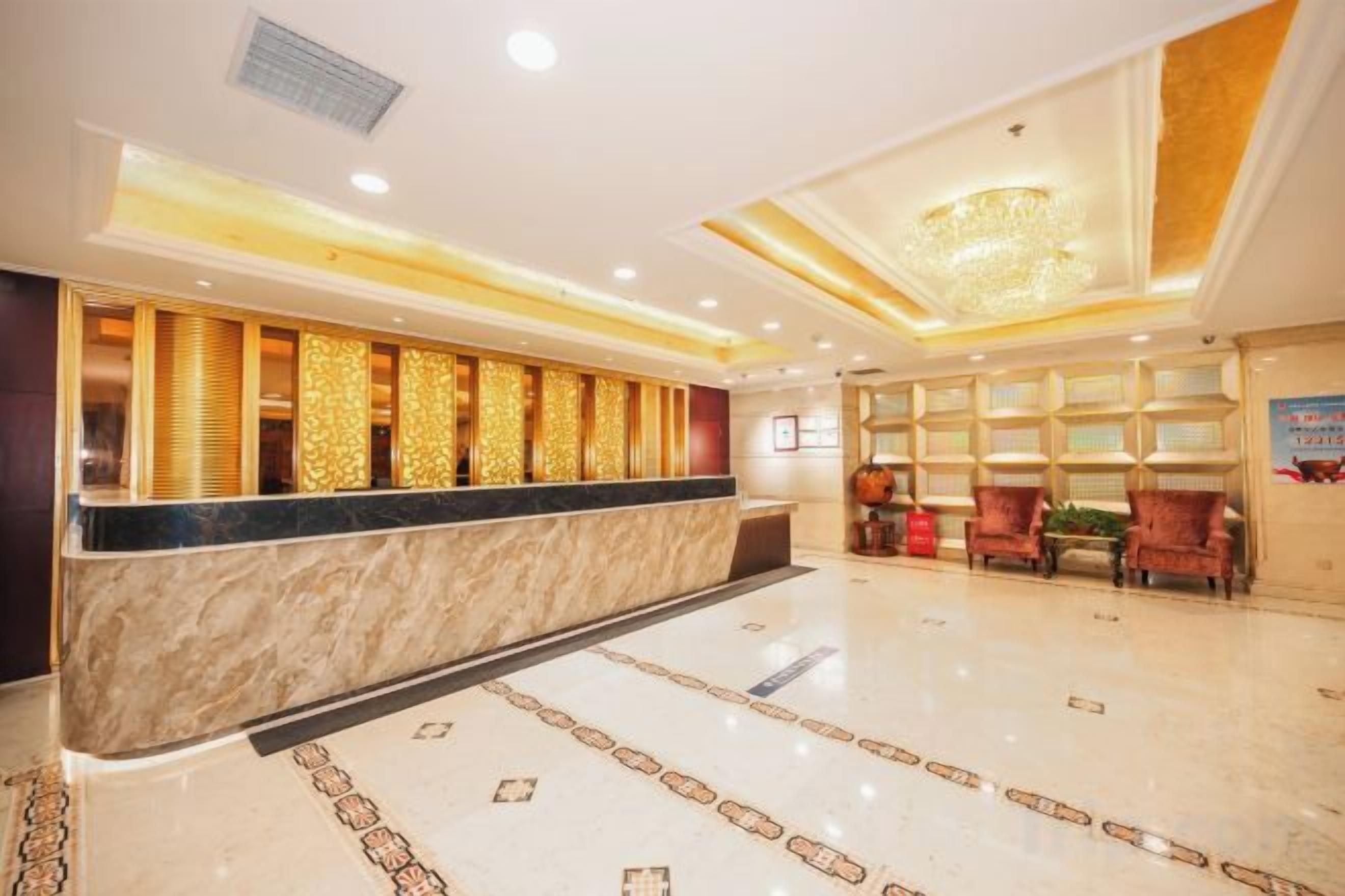 Un vestíbulo de hotel con mostrador de recepción, zona de estar y un candelabro.