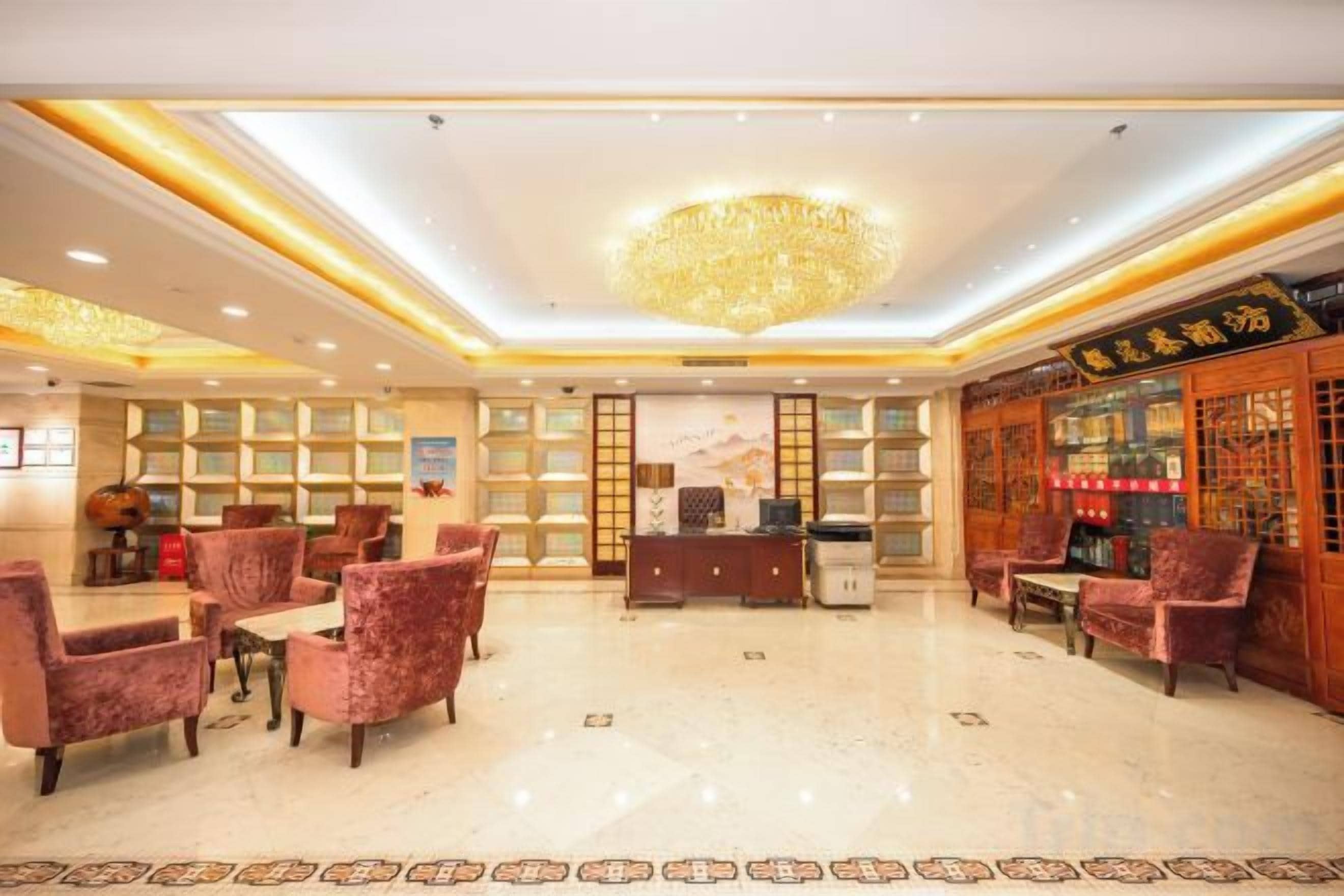 A hotel lobby with a chandelier, seating area, reception desk, and a bar.