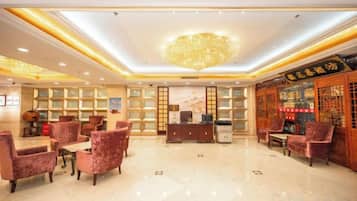 A hotel lobby with a chandelier, seating area, reception desk, and a bar.