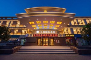 A hotel entrance with a modern design, featuring a curved roof and multiple illuminated windows.