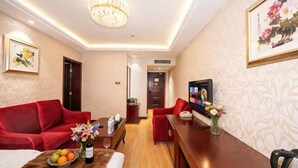 A hotel room with a red sofa, a wooden dining table, a TV, and a chandelier. - Changxin International Hotel (Lanzhou)