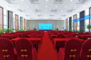 A conference room with rows of tables and chairs, a large screen at the front, and a red carpet. - Changxin International Hotel (Lanzhou)