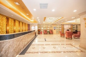 A hotel lobby with a reception desk, seating area, and decorative wall panels.
