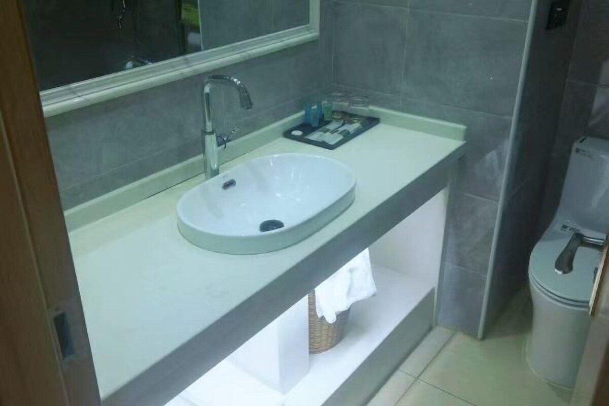 A bathroom with a white sink, a mirror, a towel rack, and a toilet.