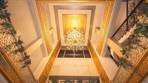 A grand staircase with a chandelier, ornate wall designs, and a floral arrangement at the top. - Changxin International Hotel (Lanzhou)
