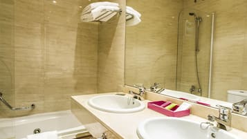 A bathroom with two sinks, a bathtub, and a shower.