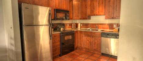 A kitchen with wooden cabinets, stainless steel appliances, and a tiled floor.