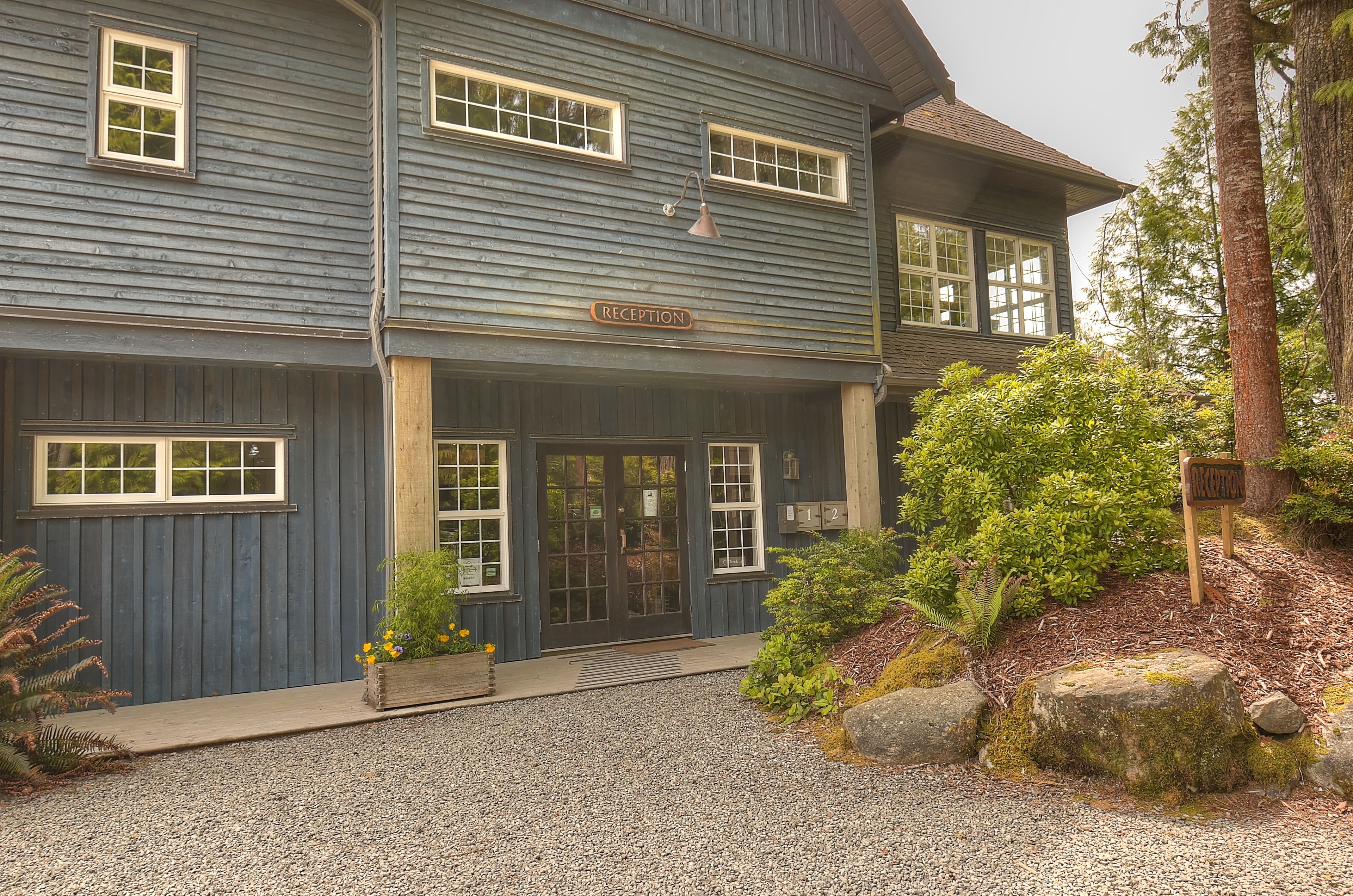 A two-story building with a reception area, large windows, and a gravel driveway.