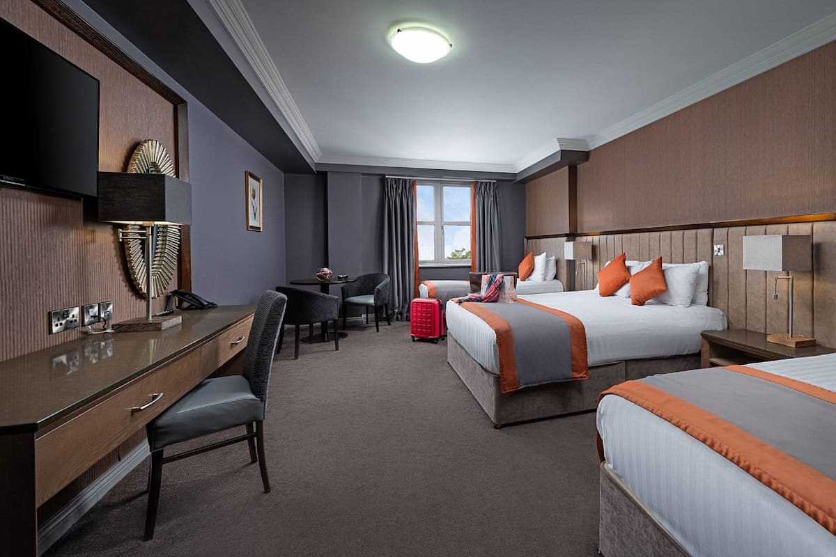 Een hotelkamer met twee bedden, een bureau en een stoel.