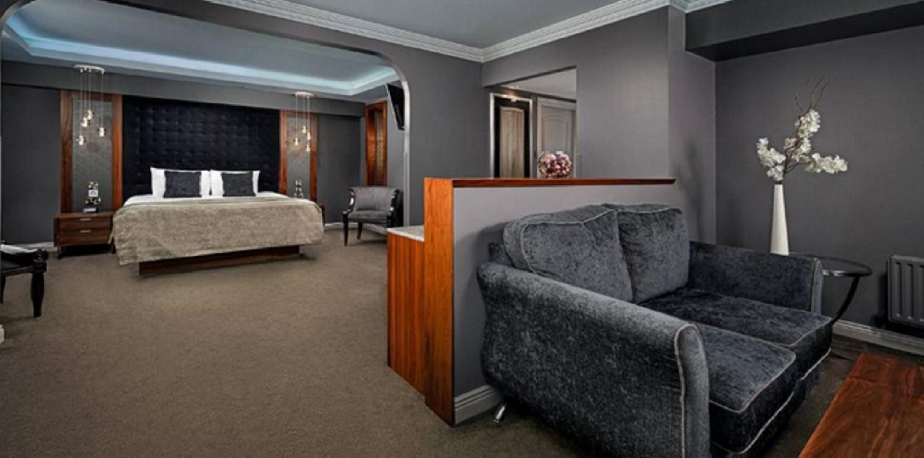 Una habitación de hotel moderna con una cama grande, una zona de estar con sofá y una mesita.