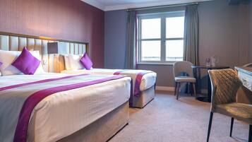 A hotel room with two beds, a desk, a chair, and a window with curtains.