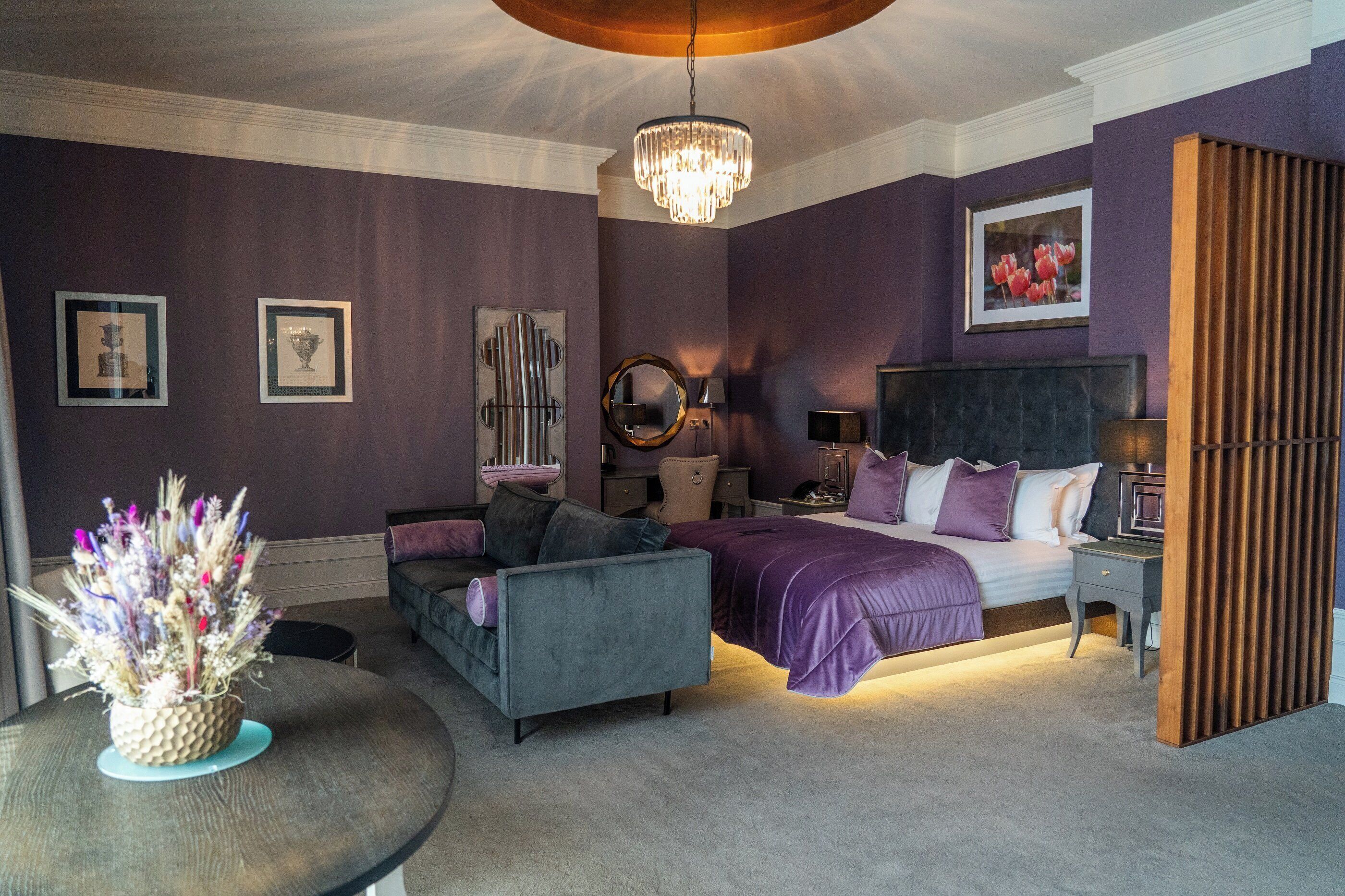 A bedroom with a bed, a chair, a table, and a decorative vase.