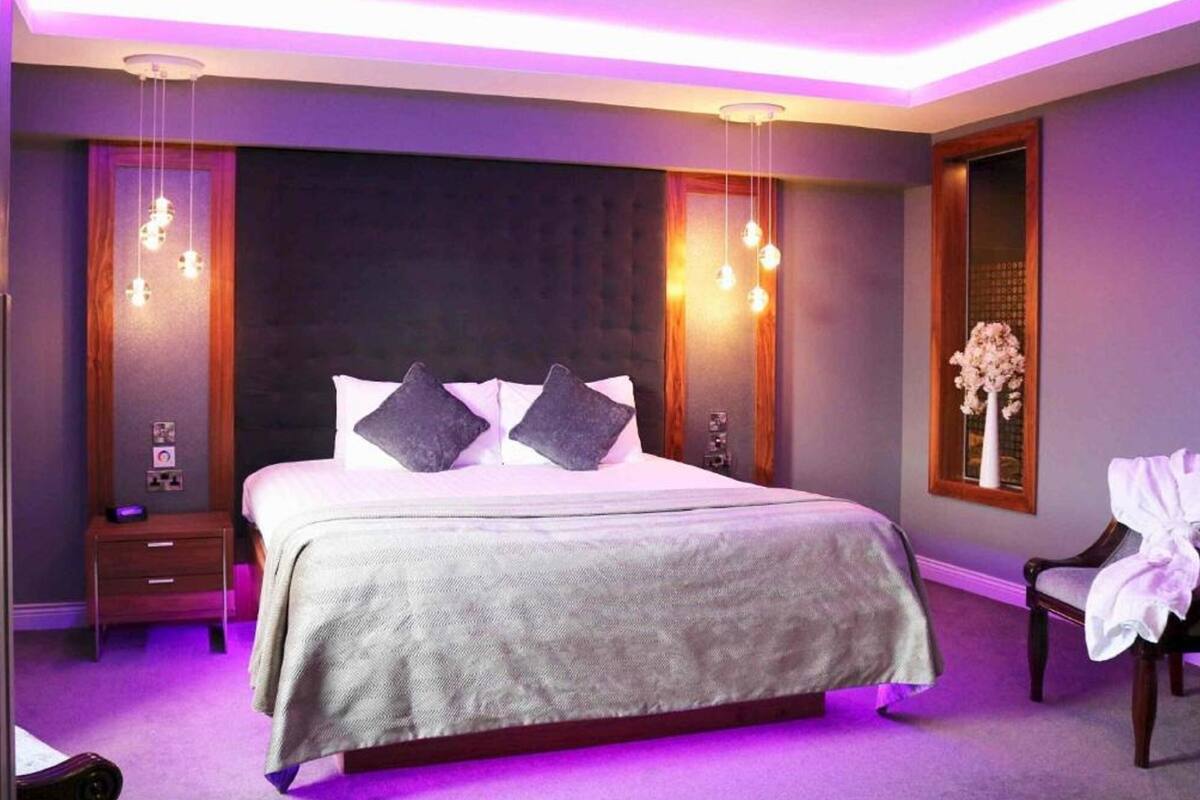 Een moderne slaapkamer met een groot bed, twee nachtkastjes en een bijpassend tafeltje.