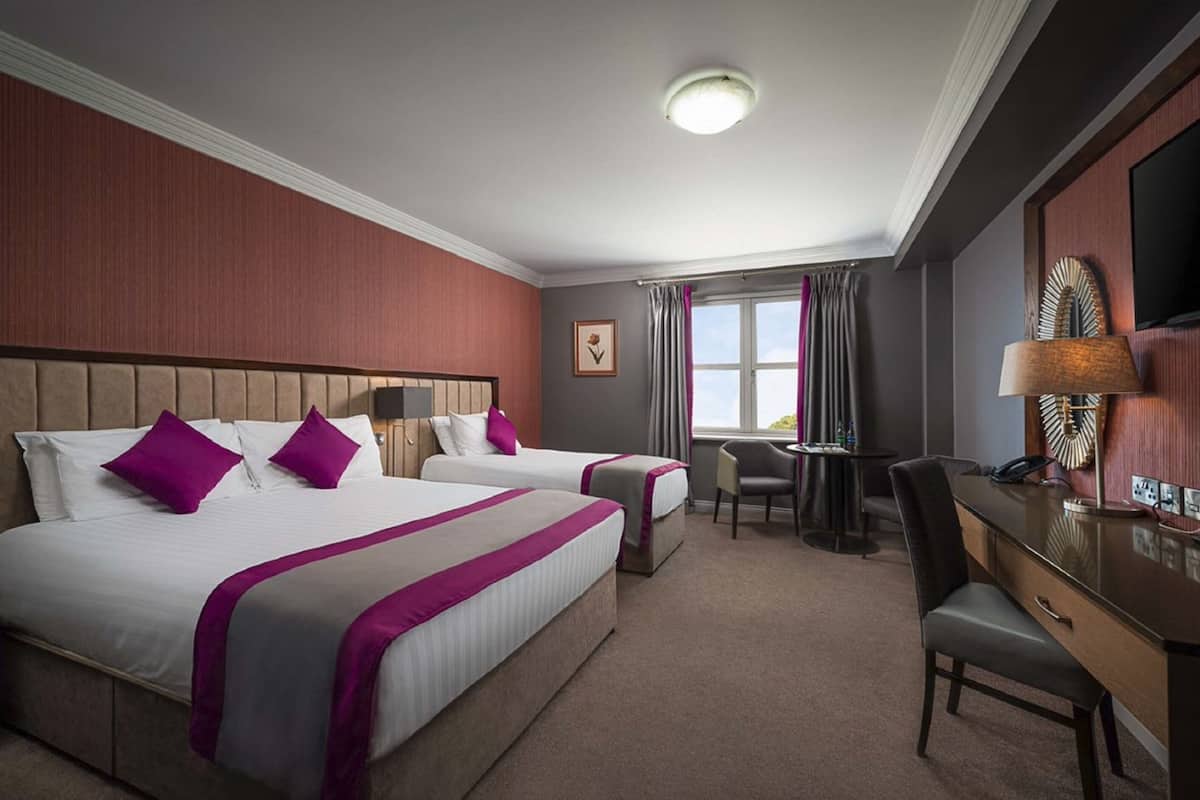 Een hotelkamer met twee bedden, een bureau, een stoel en een televisietoestel.