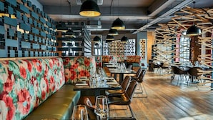 L'intérieur d'un restaurant avec un long comptoir, des banquettes et un mur orné de motifs.