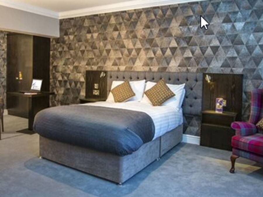 A bedroom with a bed, a chair, and a nightstand.