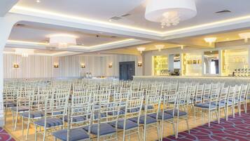 A conference room with rows of chairs, a bar area, and a stage.