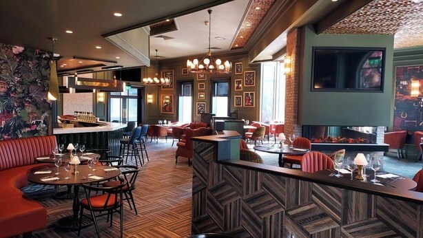 A restaurant with a bar area, seating arrangements, and a fireplace. - Talbot Hotel Midleton (Midleton)