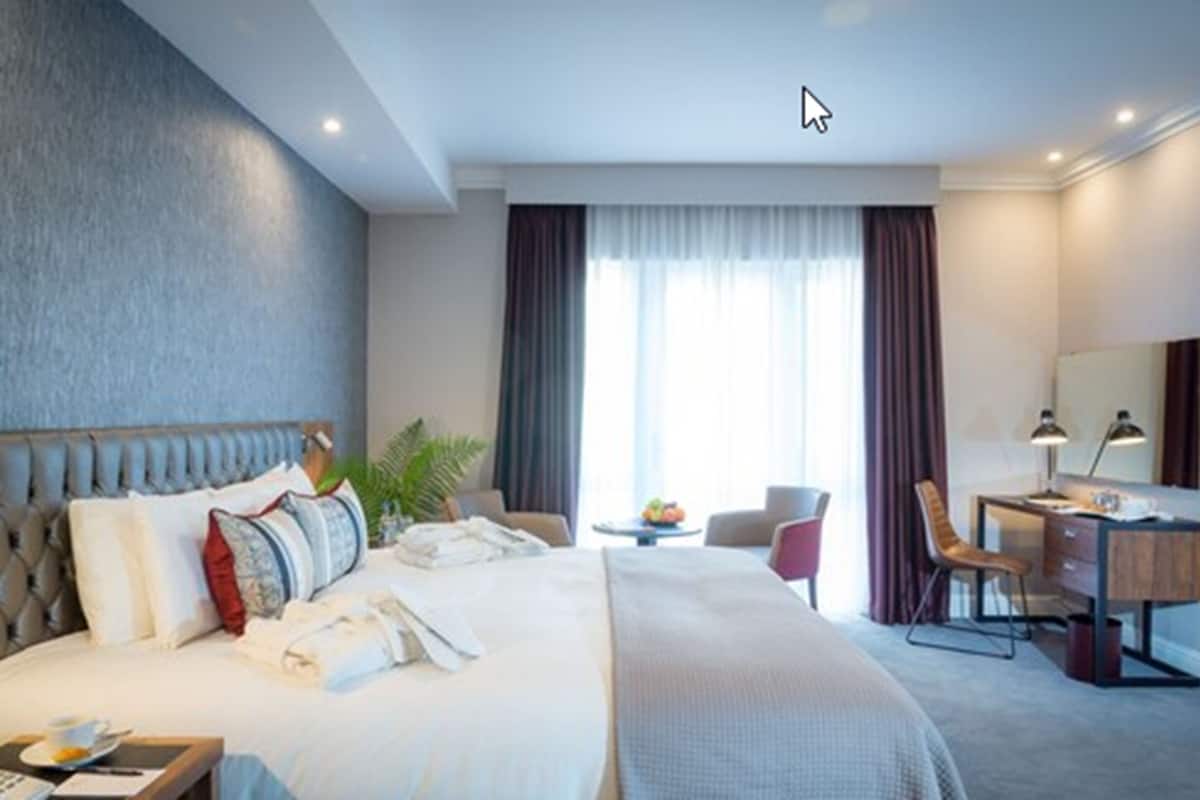 Une chambre d’hôtel avec un grand lit, un bureau, une chaise et une petite table sur laquelle se trouvent des fruits.