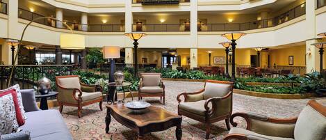 A multi-level hotel lobby with a central seating area, multiple floors, and a decorative garden.