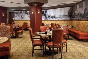 A restaurant with booths and tables, patterned carpet, and wall art.