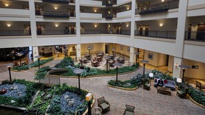 Un atrium d’hôtel à plusieurs niveaux, doté d’une cour centrale, de nombreux espaces de détente et d’un bar situé au niveau inférieur.