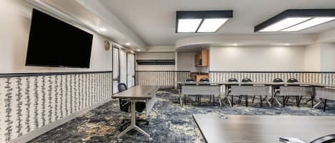 Un salón de conferencias con una pantalla plana grande, un reloj y una pared con diseño.
