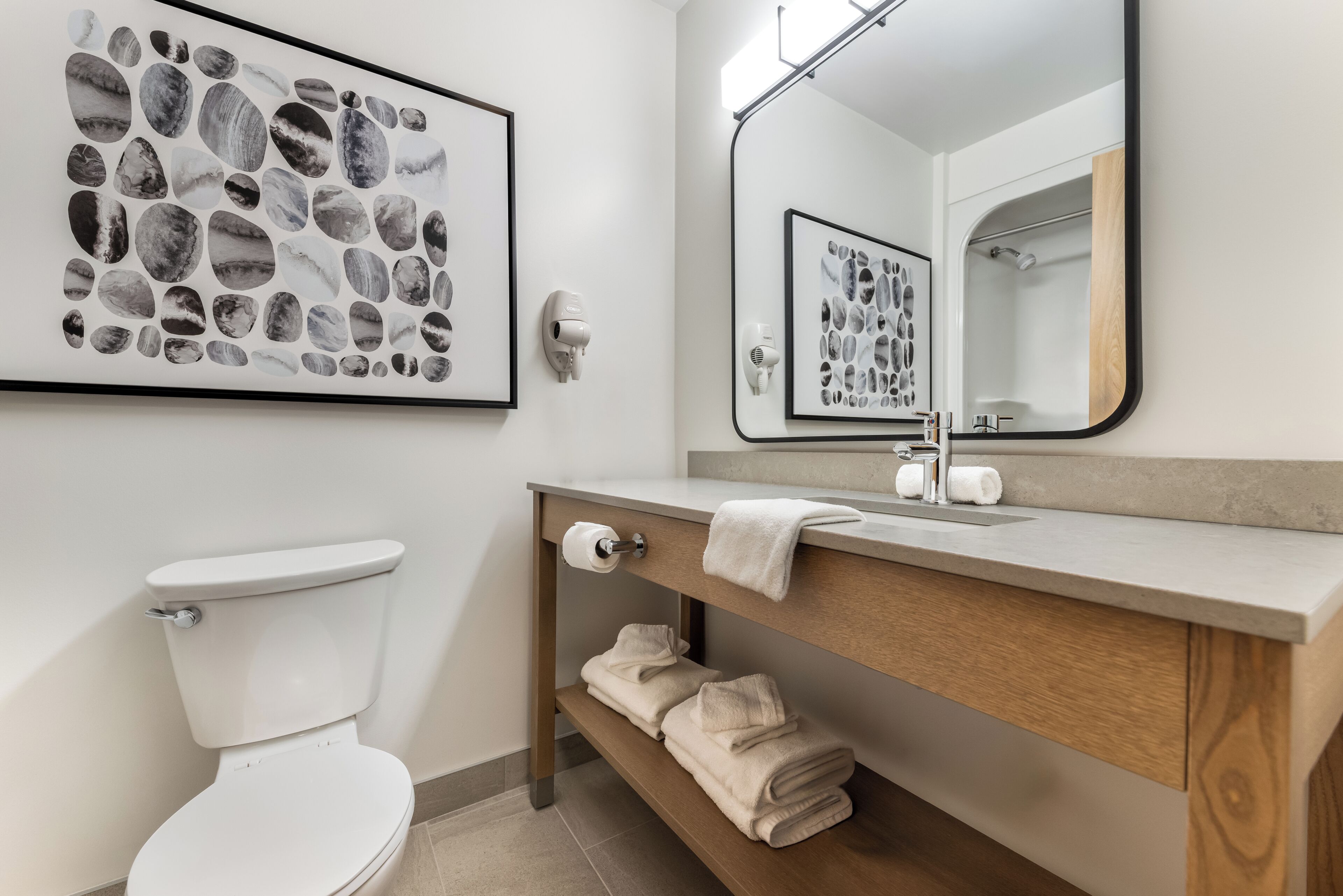 A modern bathroom with a toilet, a sink, a mirror, and a towel rack.