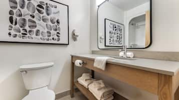 A modern bathroom with a toilet, a sink, a mirror, and a towel rack.