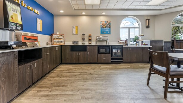 A modern kitchen area with a breakfast bar, a coffee machine, and a large window providing natural light. - Days Inn & Suites by Wyndham Thunder Bay (Thunder Bay)