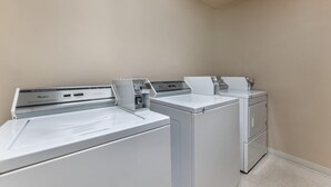 A laundry room with two front-loading washers and a dryer. - Days Inn & Suites by Wyndham Thunder Bay (Thunder Bay)