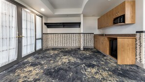 A compact kitchen with a microwave, wooden cabinets, and a patterned floor. - Days Inn & Suites by Wyndham Thunder Bay (Thunder Bay)