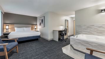 A hotel room with a bed, desk, chair, and a large bathtub.