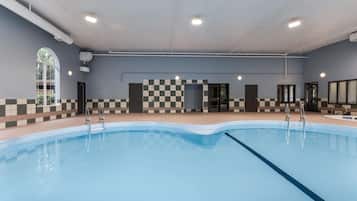 A swimming pool with a checkered wall pattern, a tiled floor, and a ceiling with recessed lighting.